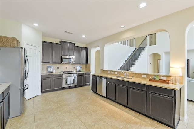 19538 Salt Grass Meadow Dr, Cypress, TX 77433 - kitchen with stainless steel appliances, arched walkways, backsplash, light countertops, and recessed lighting
