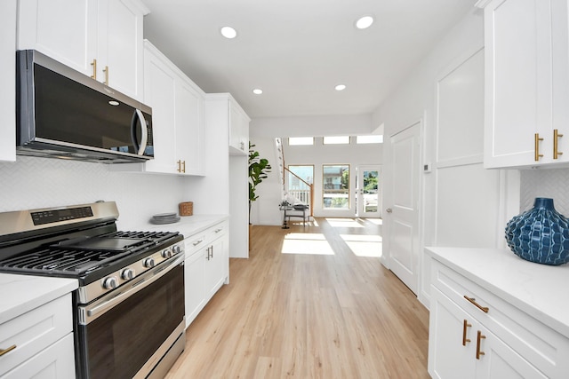 300 Narcissus Rd, Clear Lake Shores, TX 77565 - kitchen featuring appliances with stainless steel finishes, white cabinetry, light wood-style flooring, recessed lighting, and light stone counters