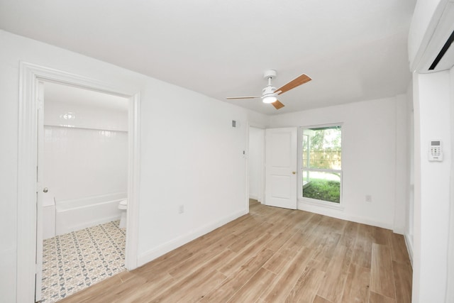 300 Narcissus Rd, Clear Lake Shores, TX 77565 - unfurnished bedroom with a wall mounted air conditioner, light wood-style floors, connected bathroom, and ceiling fan