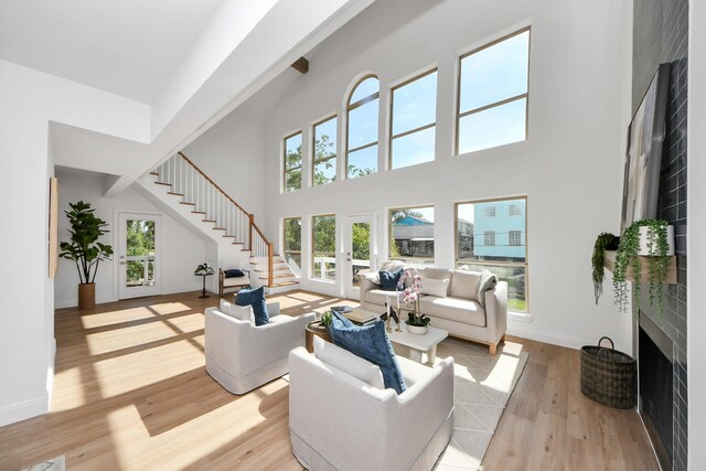 300 Narcissus Rd, Clear Lake Shores, TX 77565 - living room featuring a large fireplace, a high ceiling, stairway, and light wood-type flooring