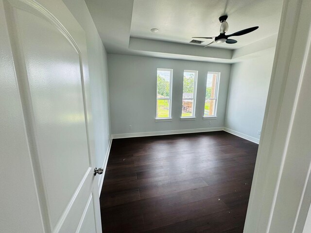 8128 Penrod St, Houston, TX 77028 - empty room featuring a raised ceiling, dark wood-style floors, and a ceiling fan