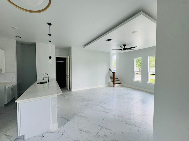 8128 Penrod St, Houston, TX 77028 - kitchen featuring light marble finish floors, white cabinetry, hanging light fixtures, open floor plan, and a ceiling fan