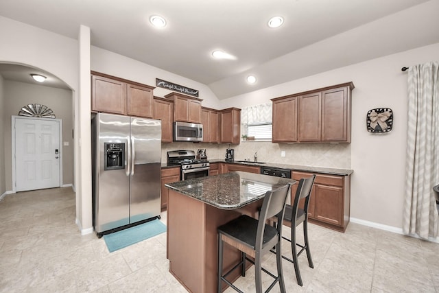 18614 Magnolia Dell Dr, Cypress, TX 77433 - kitchen featuring appliances with stainless steel finishes, arched walkways, decorative backsplash, a kitchen bar, and lofted ceiling