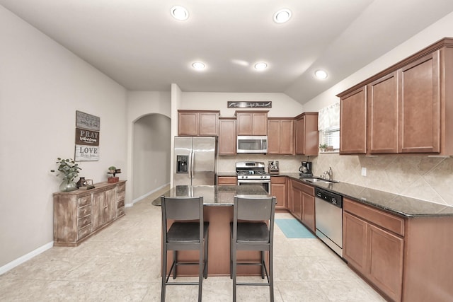18614 Magnolia Dell Dr, Cypress, TX 77433 - kitchen featuring appliances with stainless steel finishes, a breakfast bar area, arched walkways, a center island, and dark stone countertops