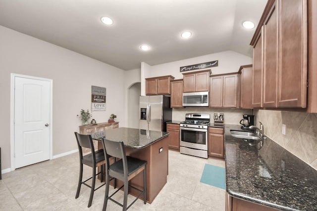 18614 Magnolia Dell Dr, Cypress, TX 77433 - kitchen with stainless steel appliances, arched walkways, a kitchen island, a kitchen bar, and dark stone countertops