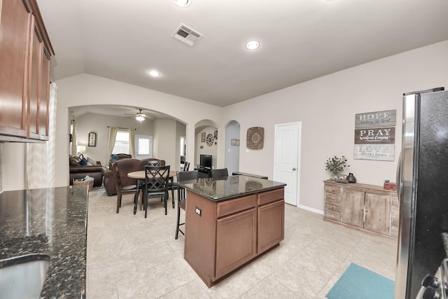 18614 Magnolia Dell Dr, Cypress, TX 77433 - kitchen featuring arched walkways, freestanding refrigerator, open floor plan, dark stone countertops, and a center island