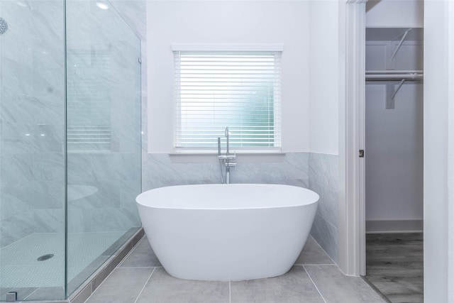 10513 Chesterfield Dr, Houston, TX 77051 - bathroom featuring a spacious closet, a soaking tub, tiled shower, tile walls, and tile patterned flooring