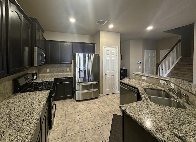 17410 Sandalisle Ln, Richmond, TX 77407 - kitchen featuring appliances with stainless steel finishes, dark stone counters, tasteful backsplash, light tile patterned floors, and dark cabinetry