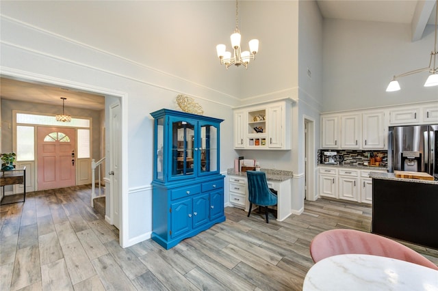 5631 Spring Lodge Dr, Houston, TX 77345 - kitchen with stainless steel fridge with ice dispenser, a high ceiling, a chandelier, white cabinets, and light wood-style flooring