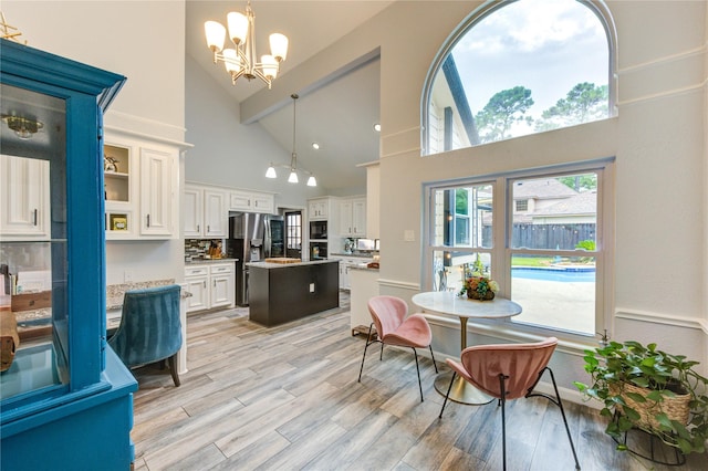 5631 Spring Lodge Dr, Houston, TX 77345 - kitchen featuring stainless steel refrigerator with ice dispenser, a center island, high vaulted ceiling, a chandelier, and light wood-type flooring