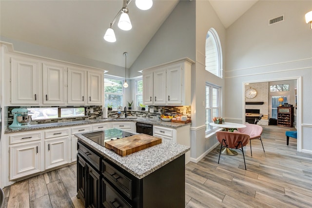 5631 Spring Lodge Dr, Houston, TX 77345 - kitchen with black appliances, white cabinetry, light stone countertops, decorative backsplash, and light wood-style flooring