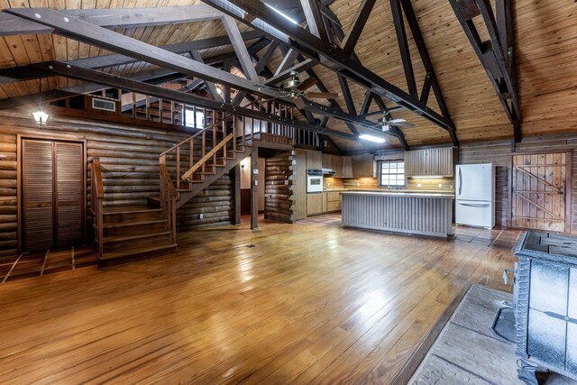 800 Fm 980 S, Point Blank, TX 77364 - unfurnished living room featuring light wood finished floors, ceiling fan, a wood ceiling with exposed beams, high vaulted ceiling, and rustic walls