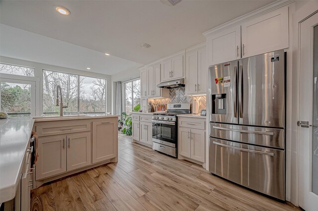 6628 Bayou Glen Rd Unit 6628, Houston, TX 77057 - kitchen with stainless steel appliances, light wood-style flooring, light countertops, backsplash, and under cabinet range hood