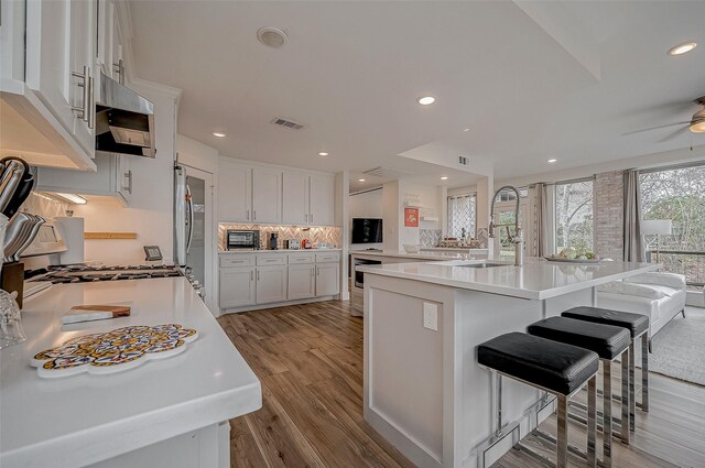 6628 Bayou Glen Rd Unit 6628, Houston, TX 77057 - kitchen with appliances with stainless steel finishes, light wood-style floors, light countertops, white cabinetry, and ceiling fan