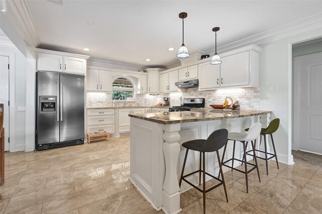 5227 Falvey St, Houston, TX 77017 - kitchen with stainless steel appliances, a peninsula, stone counters, white cabinets, and crown molding