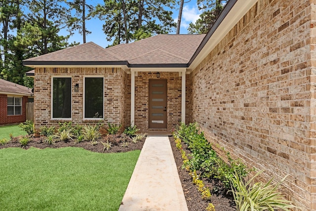 327 Paradise Ln, Montgomery, TX 77356 - view of exterior entry with roof with shingles, brick siding, and a yard