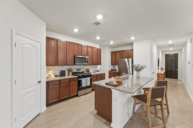 7003 Tehama Ln, Rosharon, TX 77583 - kitchen with appliances with stainless steel finishes, backsplash, light stone countertops, a breakfast bar, and recessed lighting