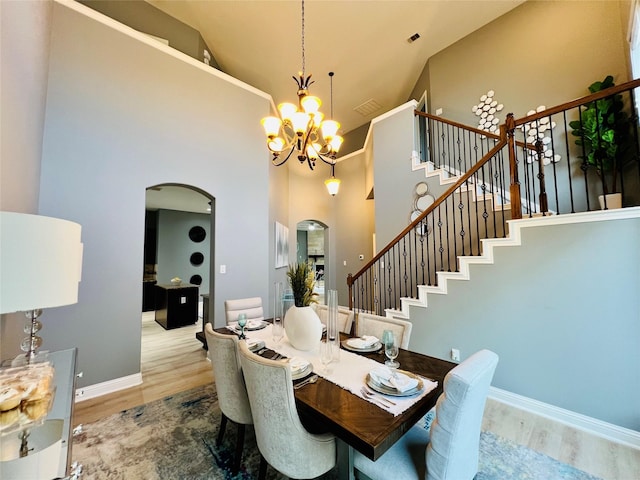 18718 Fairmont Springs Ct, Cypress, TX 77429 - dining space with arched walkways, a chandelier, wood finished floors, stairs, and high vaulted ceiling