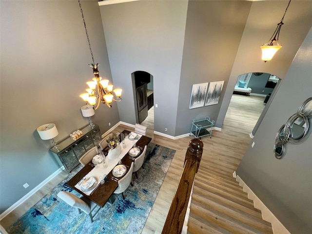 18718 Fairmont Springs Ct, Cypress, TX 77429 - dining space with arched walkways, wood finished floors, a chandelier, and a high ceiling
