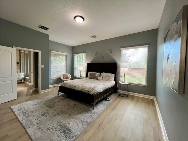 18718 Fairmont Springs Ct, Cypress, TX 77429 - bedroom featuring light wood-style floors, multiple windows, and a textured ceiling