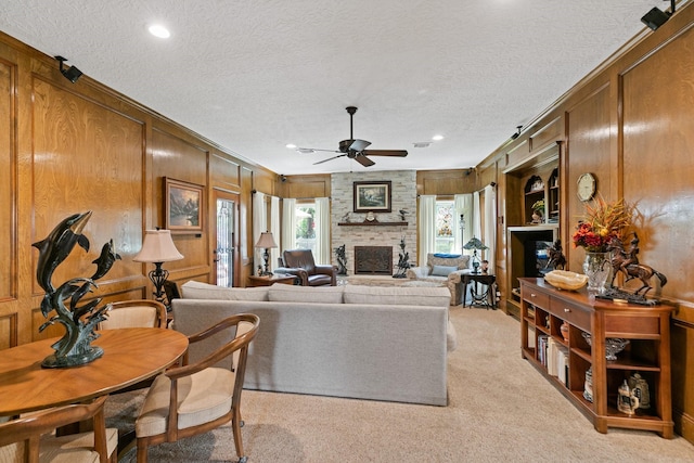 6430 Willow Pine Dr, Spring, TX 77379 - living area with a textured ceiling, ceiling fan, a large fireplace, light carpet, and wooden walls