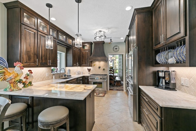6430 Willow Pine Dr, Spring, TX 77379 - kitchen with custom range hood, stainless steel appliances, dark brown cabinets, healthy amount of natural light, and a textured ceiling