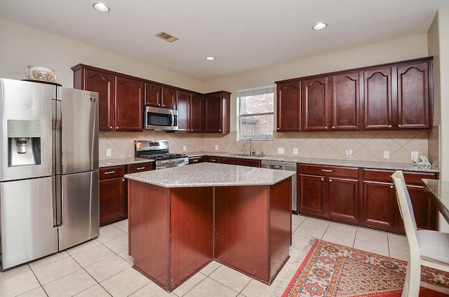 8711 Chamomile Meadow Trl, Katy, TX 77494 - kitchen with appliances with stainless steel finishes, decorative backsplash, light tile patterned flooring, a center island, and recessed lighting