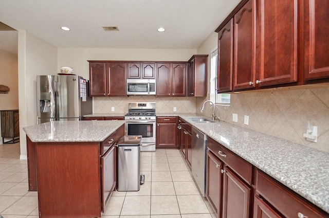 8711 Chamomile Meadow Trl, Katy, TX 77494 - kitchen featuring appliances with stainless steel finishes, a kitchen island, light tile patterned floors, light stone counters, and recessed lighting