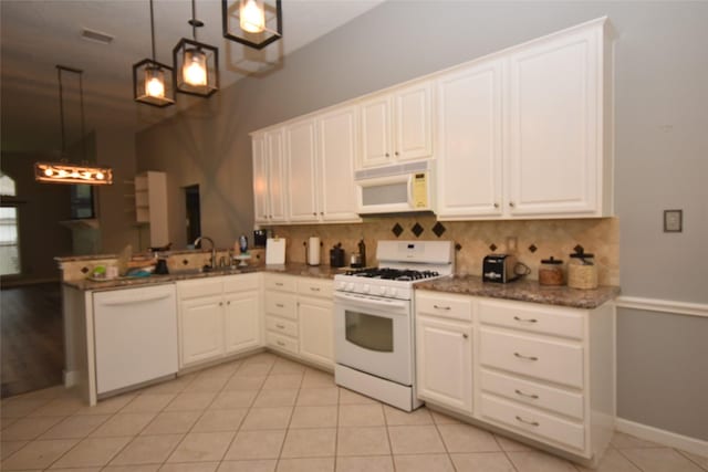 5113 Greenwater Dr, Willis, TX 77318 - kitchen with white appliances, backsplash, a peninsula, white cabinets, and dark stone countertops