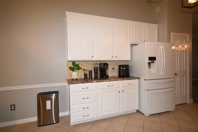 5113 Greenwater Dr, Willis, TX 77318 - kitchen with white refrigerator with ice dispenser, light tile patterned floors, backsplash, and white cabinetry