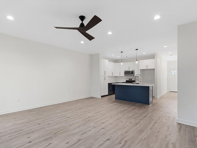 5702 Elysian St, Houston, TX 77009 - kitchen with stainless steel microwave, electric range, open floor plan, light wood-type flooring, and ceiling fan
