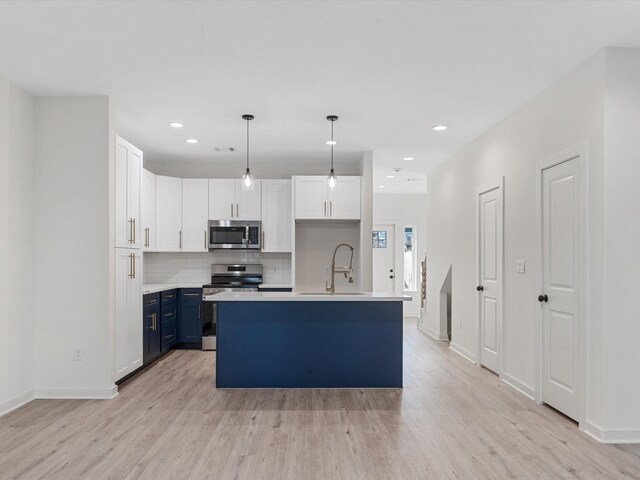 5702 Elysian St, Houston, TX 77009 - kitchen with stainless steel appliances, light wood-type flooring, blue cabinets, tasteful backsplash, and recessed lighting