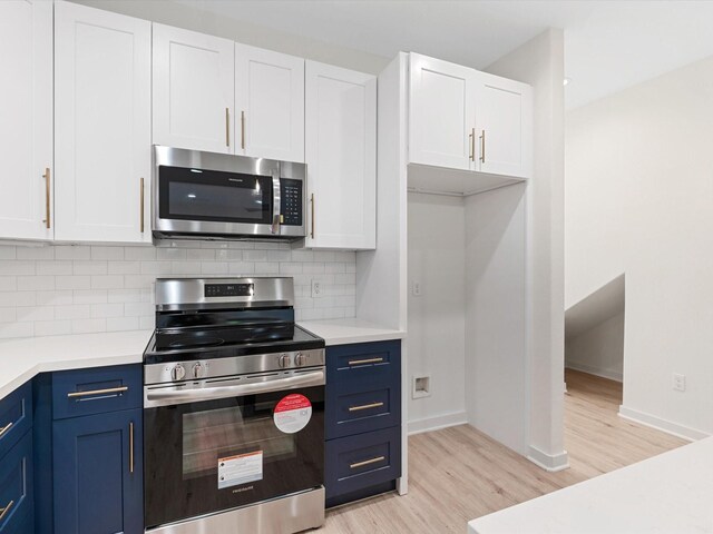 5702 Elysian St, Houston, TX 77009 - kitchen with appliances with stainless steel finishes, light wood-style flooring, blue cabinetry, and white cabinetry