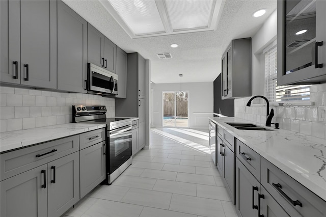 15810 Parksley Dr, Houston, TX 77059 - kitchen with stainless steel appliances, gray cabinets, a textured ceiling, tasteful backsplash, and light stone countertops