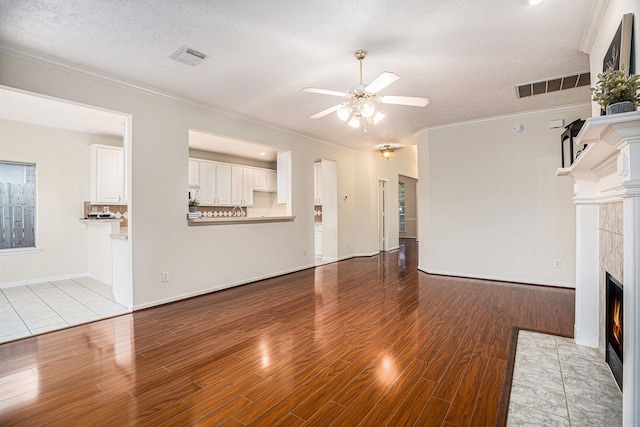 1726 Roaring Springs Ln, Seabrook, TX 77586 - unfurnished living room featuring ceiling fan, a fireplace, wood finished floors, ornamental molding, and a textured ceiling