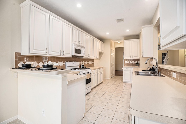 1726 Roaring Springs Ln, Seabrook, TX 77586 - kitchen with white appliances, a peninsula, tasteful backsplash, light tile patterned flooring, and white cabinets