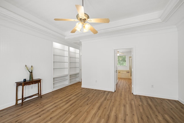34310 High Point Dr, Magnolia, TX 77355 - spare room featuring wood finished floors, crown molding, ceiling fan, built in features, and a tray ceiling