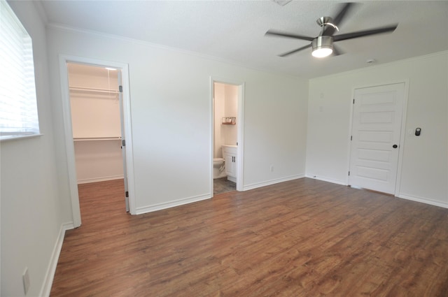 154 Wood Manor Ln, Sour Lake, TX 77659 - unfurnished bedroom with wood finished floors, a spacious closet, crown molding, a closet, and a ceiling fan