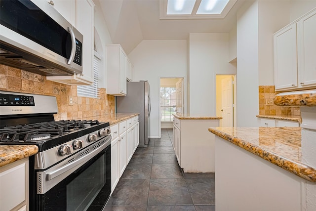 10818 Kleberg Place Dr, Houston, TX 77064 - kitchen featuring appliances with stainless steel finishes, white cabinetry, lofted ceiling, a center island, and decorative backsplash