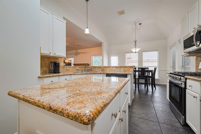 10818 Kleberg Place Dr, Houston, TX 77064 - kitchen with appliances with stainless steel finishes, decorative backsplash, a kitchen island, lofted ceiling, and white cabinetry
