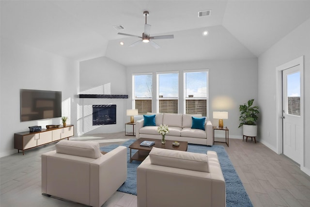 304 E Tranquil Fields Ln, Waller, TX 77484 - living room featuring lofted ceiling, plenty of natural light, light wood finished floors, a glass covered fireplace, and a ceiling fan