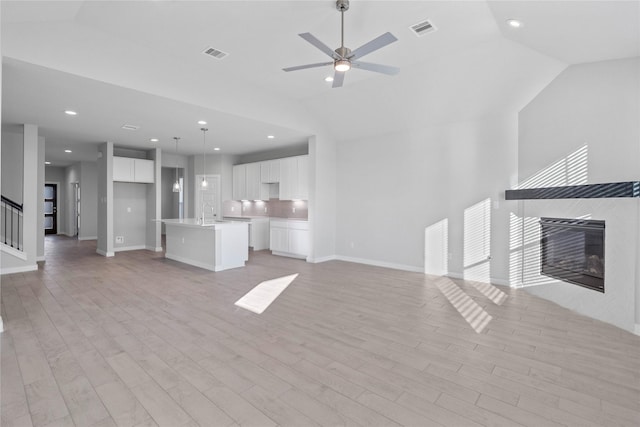 304 E Tranquil Fields Ln, Waller, TX 77484 - unfurnished living room with a tile fireplace, vaulted ceiling, light wood finished floors, ceiling fan, and recessed lighting