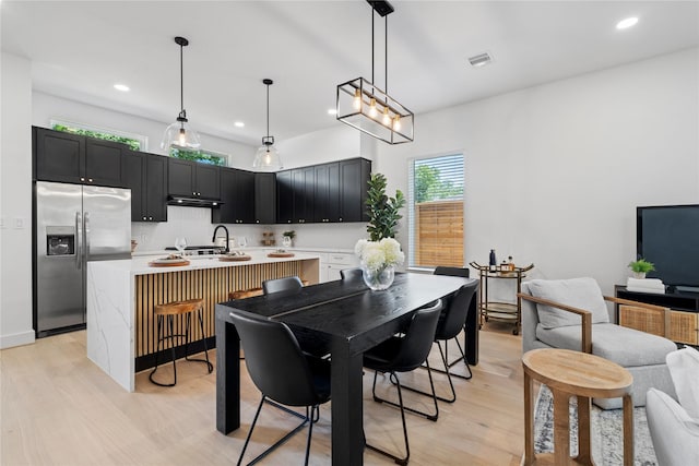 4110 Cortlandt St, Houston, TX 77018 - kitchen with stainless steel refrigerator with ice dispenser, light countertops, light wood-style flooring, under cabinet range hood, and recessed lighting
