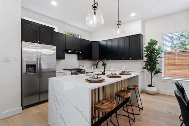 4110 Cortlandt St, Houston, TX 77018 - kitchen with appliances with stainless steel finishes, dark cabinets, light stone counters, under cabinet range hood, and light wood-type flooring