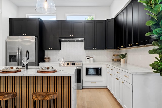 4110 Cortlandt St, Houston, TX 77018 - kitchen featuring appliances with stainless steel finishes, light stone counters, light wood-style flooring, backsplash, and dark cabinetry