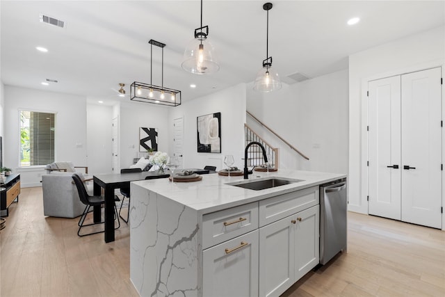 4110 Cortlandt St, Houston, TX 77018 - kitchen with stainless steel dishwasher, light wood-style floors, decorative light fixtures, a center island with sink, and light stone countertops