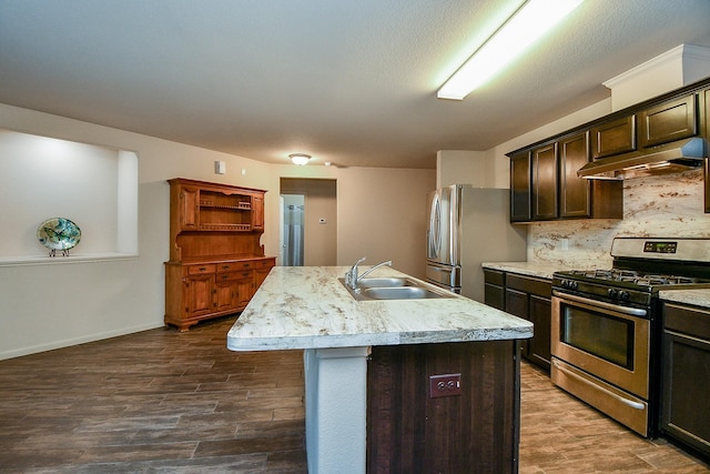 2026 Naplechase Crest Dr, Spring, TX 77373 - kitchen with appliances with stainless steel finishes, under cabinet range hood, light countertops, a center island with sink, and dark brown cabinets