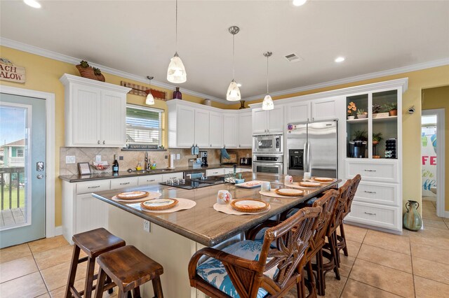2617 Breaker Dr, Port Bolivar, TX 77650 - kitchen featuring stainless steel appliances, dark countertops, light tile patterned flooring, a breakfast bar, and crown molding