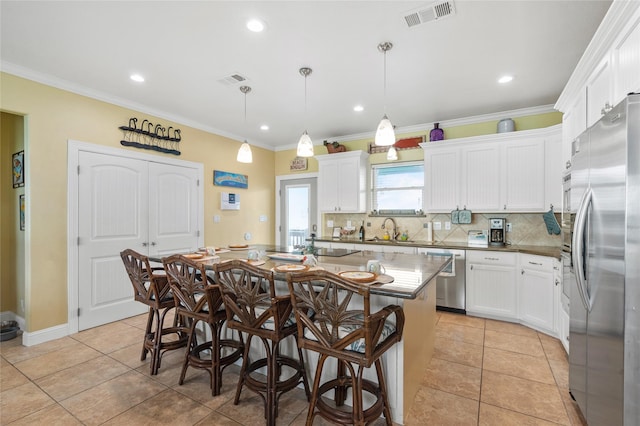 2617 Breaker Dr, Port Bolivar, TX 77650 - kitchen featuring stainless steel appliances, a center island, backsplash, white cabinetry, and a breakfast bar area