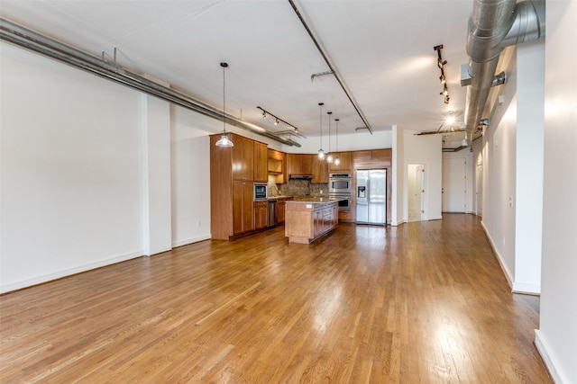1616 Fountain View Dr Unit 202, Houston, TX 77057 - kitchen featuring brown cabinetry, open floor plan, appliances with stainless steel finishes, backsplash, and light wood-style flooring